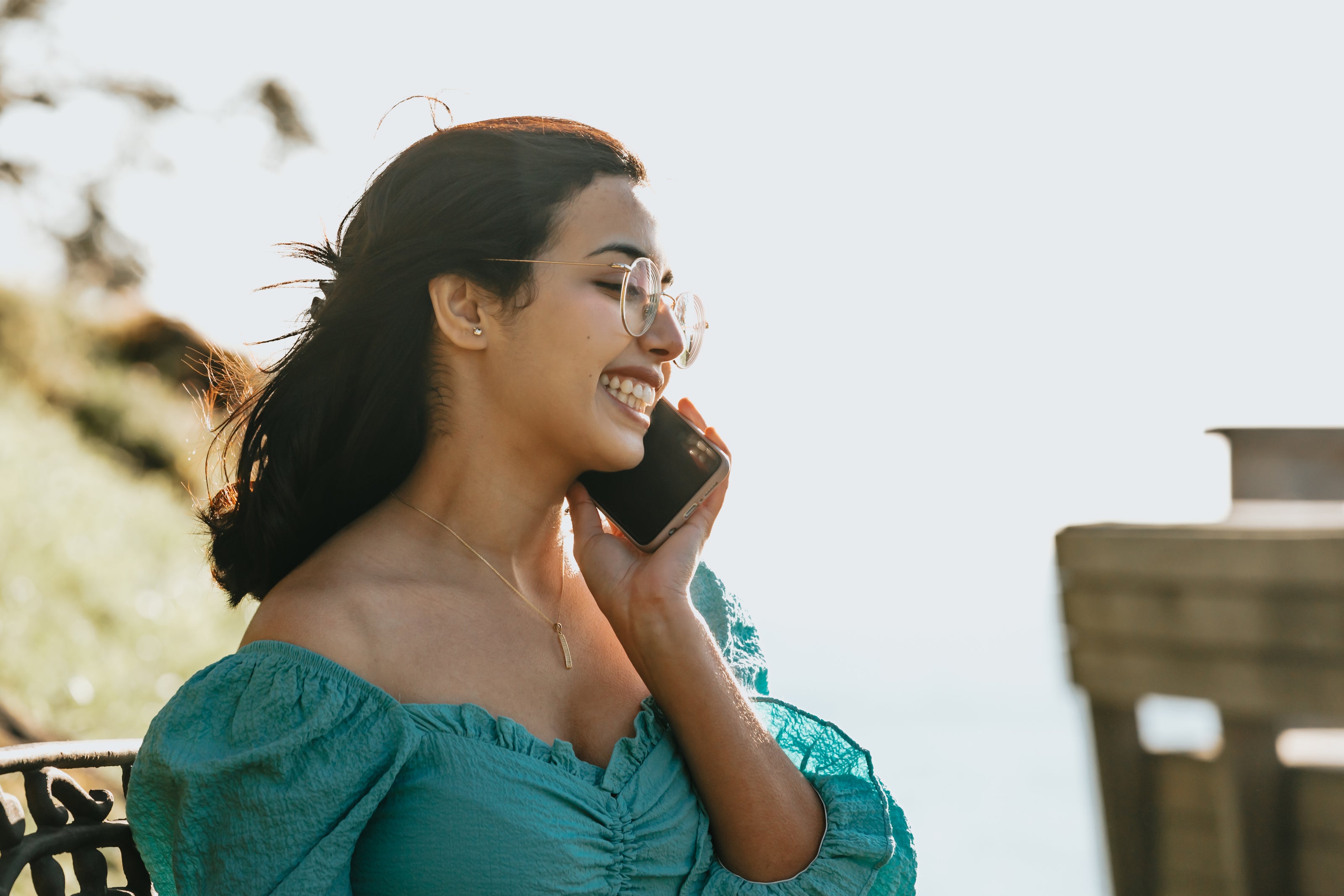 Woman smiling on the phone wearing glasses.